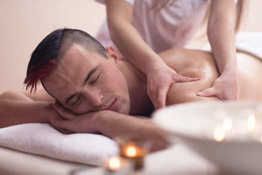 Positive young man having a back massage in a spa center