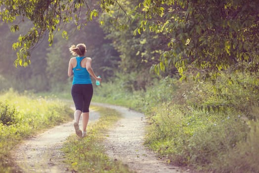 young woman enjoying in a healthy lifestyle while jogging along a country road, exercise and fitness concept