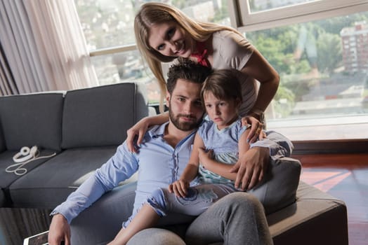 happy couple spending time with kids using tablet computer on an armchair  at home