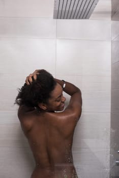 Woman in the shower,beautiful black young female showering under refreshing water, healthy lifestyle, enjoying time in luxury spa resort