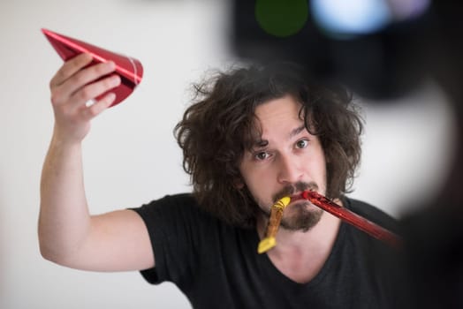 Portrait of a man in party hat blowing in whistle isolated on a white background