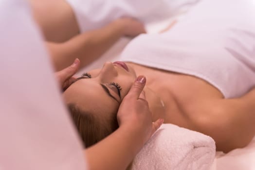 Young beautiful relaxed woman receiving a head massage in a spa centre