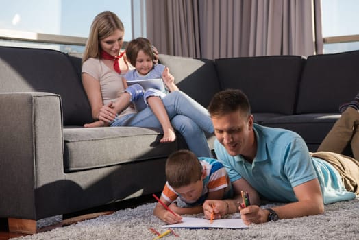 Happy Young Family Playing Together at home on the floor using a tablet and a children's drawing set