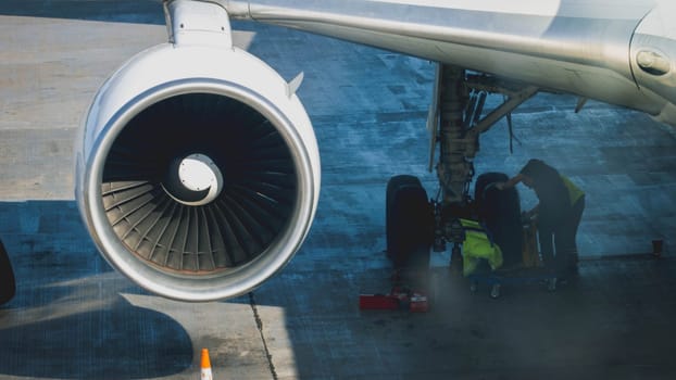 Ground service crew repairing and preparing airplane for flight in airport.