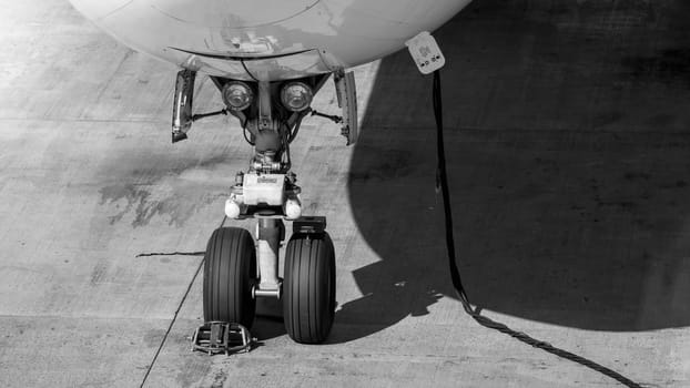 Black and white photo of electric power cable and front chassis of airplane during maintenane