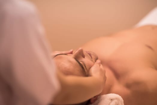 Young  relaxed man receiving a head massage in a spa centre