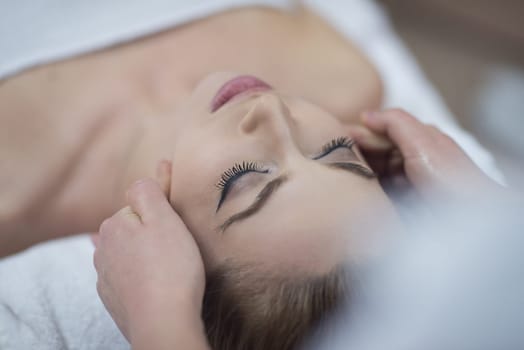 Young beautiful relaxed woman receiving a head massage in a spa centre