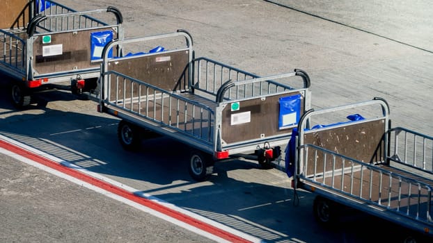 Empty baggage transportation cars on airport runway.