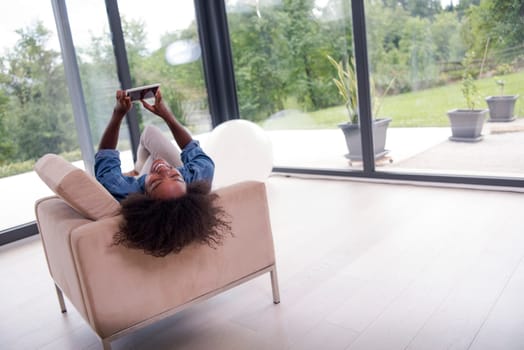 Young african american woman at home relaxing in her luxury lliving room reading a digital tablet PC surf internet and work