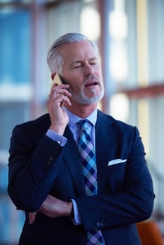 senior business man talk on mobile phone  at modern bright office interior