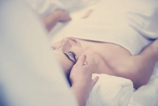 beautiful young woman getting face and head  massage in spa and wellness salon