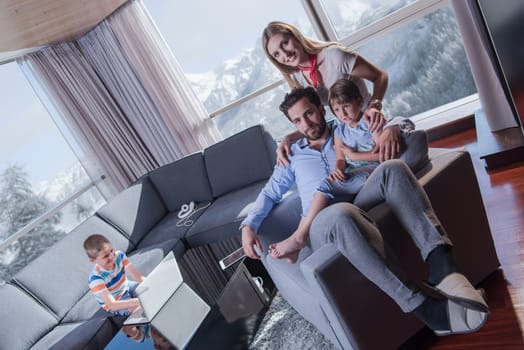 happy couple spending time with kids using tablet computer on an armchair  at home