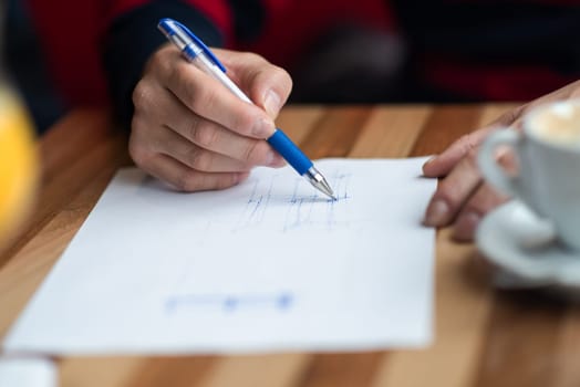 The hand of the designer with a pen, designing and sketching his idea for a furniture product