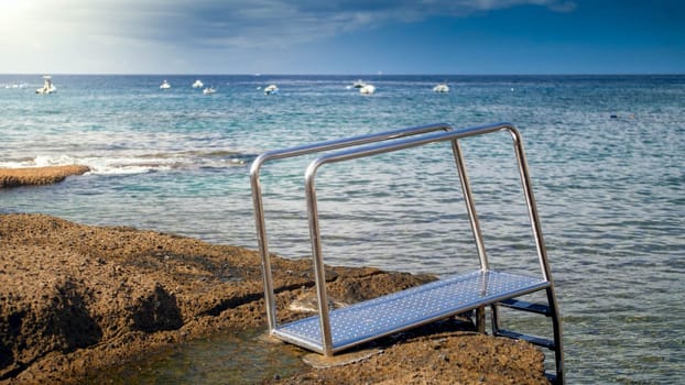 Metal ladder from the stone pier in ocean lagoon.