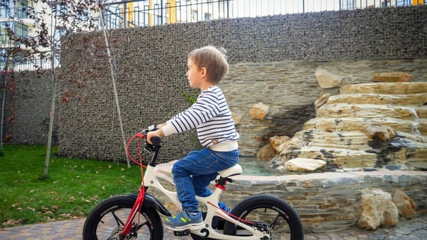 Happy cheerful boy with helmet riding bicycle on street.
