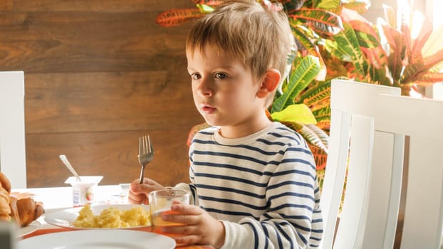 Portrait of little 3 years old boy sitting behind dining table while having breakfast.