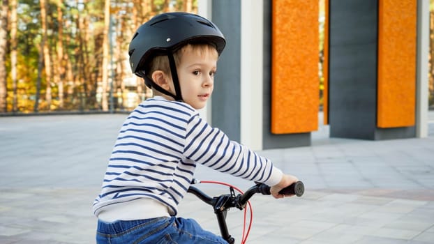 Portrait of little toddler boy weraing protective helmet riding his bicycle.