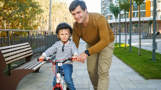 Portrait of happy smiling man teaching his son riding first bicycle.