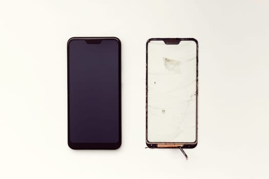 Repair and replacement of a mobile phone touchscreen. Refurbished smartphone and non-working touchscreen on a white background. View from above