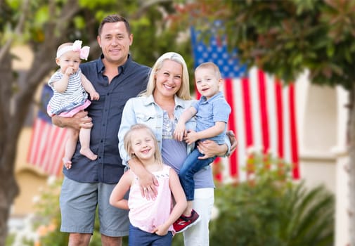 Happy Young Caucasian Family In Front of Houses with American Flags.