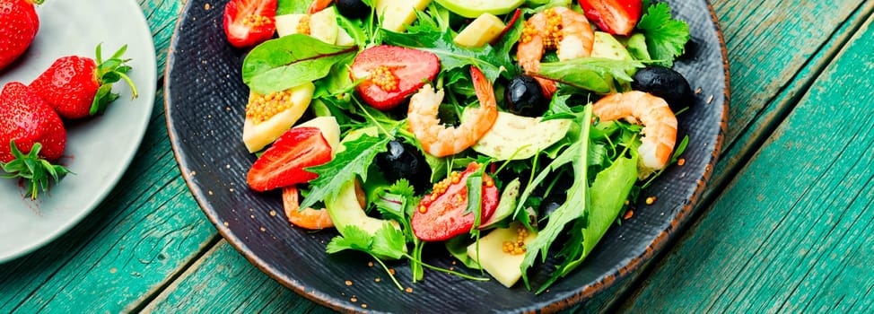 Diet salad with shrimps,strawberries,avocado and green.Healthy salad in stylish metal plate