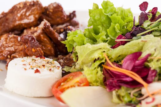 Fresh salad with fresh goat cheese and fried beef strips prepared on a plate insulated against a white background