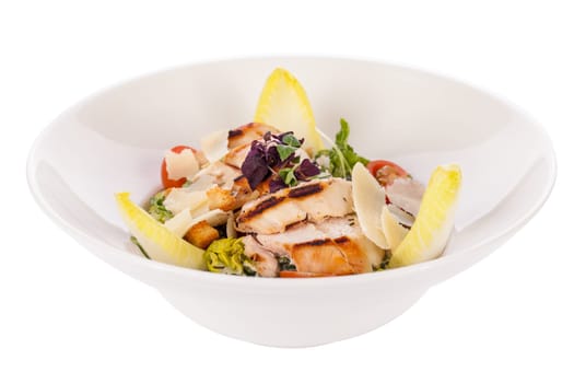 Fresh delicious caesarsalat with grilled chicken bust parmesan shards and croutons isolated against a white background