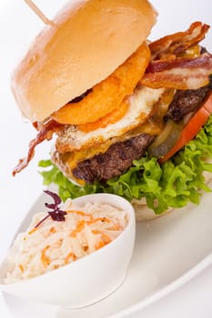 Delicious hamburger cheeseburger with bacon egg and salad on a plate isolated on a white background