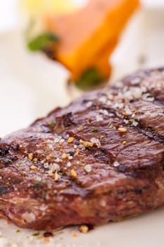 Succulent grilled beef fillet steak with homemade herb butter on a plate isolated against a white background