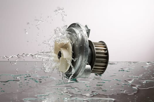 Auto parts, engine cooling pump in water splash on gray gradient background