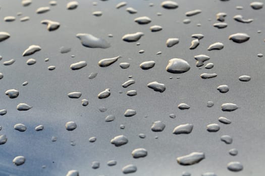 drops on a gray mirror surface which reflects the sky