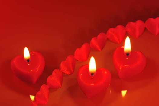 Three bright red candles in heart shape with fabric hearts