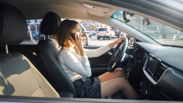 Young female driver talking by phone while looking for parking olace. Phone conversation distract driving that may cause car accident.