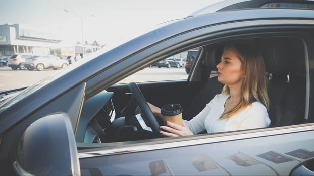 Toned portrait of female driver with coffee in paper cup commuting to work at morning.