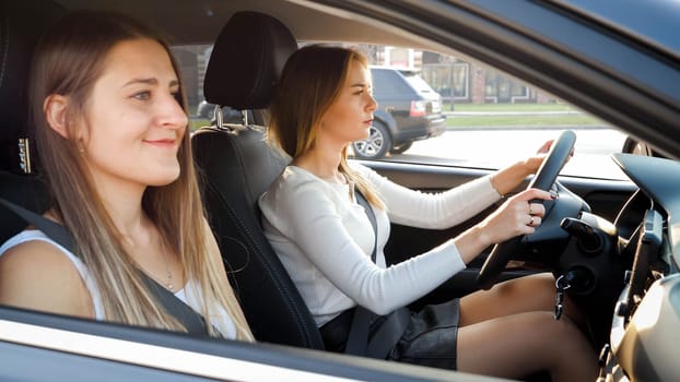 Portrait of two smiling girls riding in car at sunset.