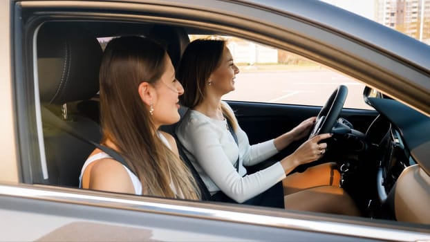 Two happy smiling girls driving a car on city street.