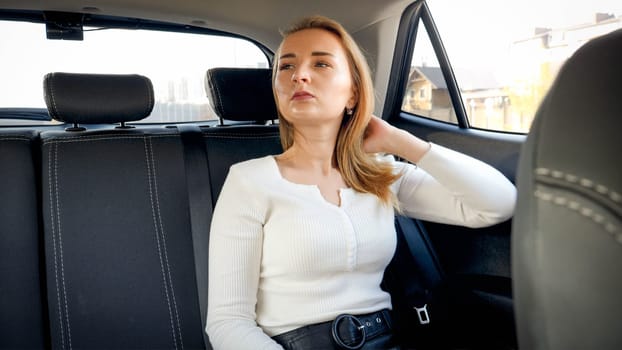 Portrait of sexy blonde woman sitting on the car back seat while riing in taxi.