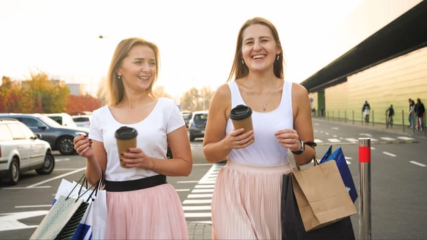 Portrait of two girls smiling and drinking coffee after having shopping in big mall.