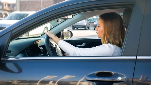 Portrait of beautiful young woman looking on the road while driving a car.