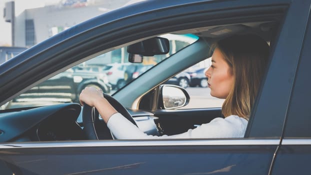Toned portrait of beautiful female driver driving a car in city.