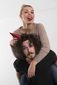 Young happy couple in party hats blowing in whistle isolated on a white background
