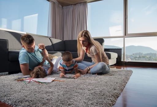 Happy Young Family Playing Together at home on the floor using a tablet and a children's drawing set