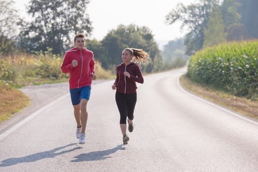 young couple enjoying in a healthy lifestyle while jogging along a country road, exercise and fitness concept