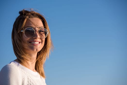 Young woman on the beach. The girl enjoying the warm autumn day. Portrait of beautiful girl near the water