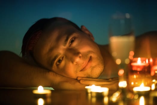 young handsome man enjoys relaxing in the jacuzzi with candles and champagne at luxury resort spa