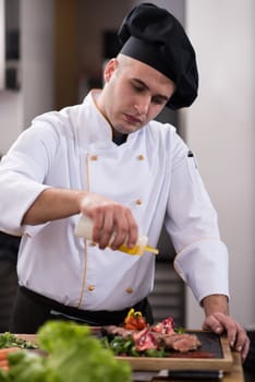 Chef finishing steak meat plate with Finally dish dressing and almost ready to serve at the table