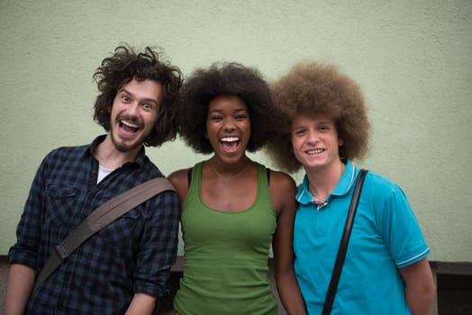 Portrait of multiethnic group of happy three friends in casual wear standing and laughing