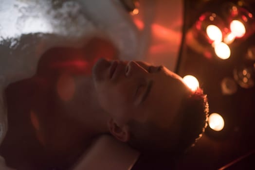 young handsome man enjoys relaxing in the jacuzzi with candles and champagne at luxury resort spa