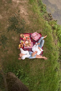 Couple in love enjoying picnic time drink and food in beautiful nature on the river bank top view