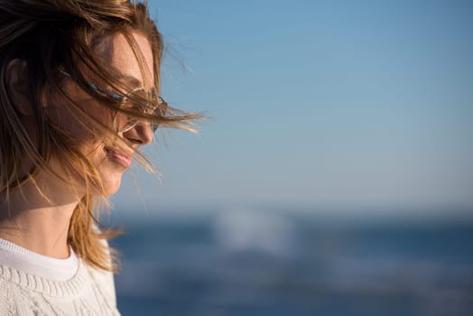 Young woman on the beach. The girl enjoying the warm autumn day. Portrait of beautiful girl near the water